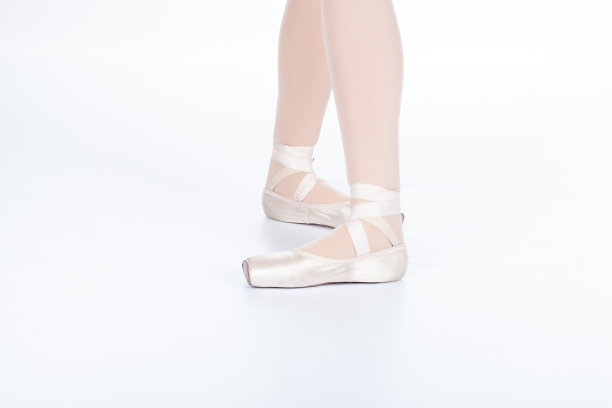 在老师的视角下，第五个姿势打开，小腿向前。年轻的芭蕾舞女演员身着粉色丝绸和缎面尖头鞋，展示各种经典的芭蕾舞脚姿势图片下载