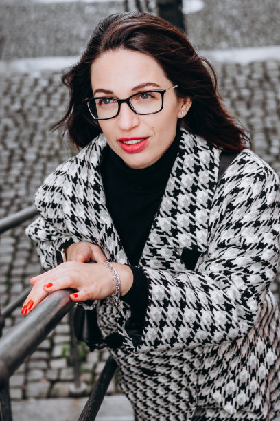 一个漂亮的黑发女人，戴着眼镜，穿着格子大衣，微笑着把目光移开图片下载