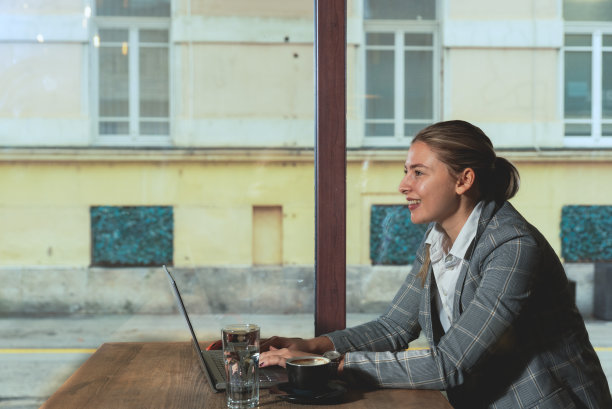 侧视图平静年轻的拉丁IT妇女在西装使用工作或学习笔记本电脑电脑喝茶坐在桌子上在咖啡店咖啡厅餐厅室内自由职业者移动办公室经营理念图片下载