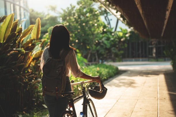 亚洲女性在城市中随意骑自行车上班，在城市中自行车通勤的环保生活方式图片下载