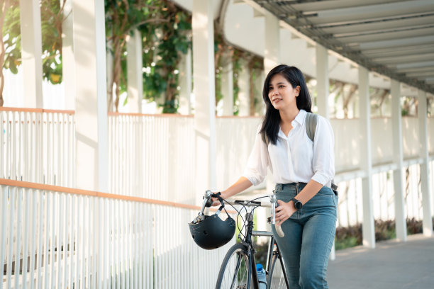 亚洲女性在城市中随意骑自行车上班，在城市中自行车通勤的环保生活方式图片下载