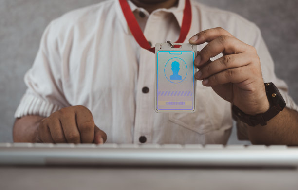 出示白色员工身份的商人坐在椅子上，键盘随时准备服务图片下载