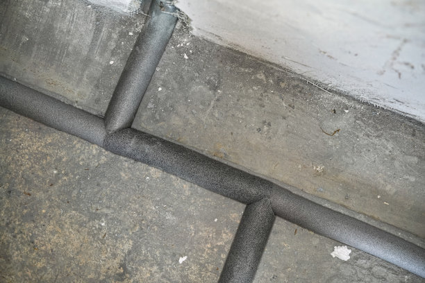 在新房子里安装了覆盖着灰色泡沫隔热材料的水管——裸露的墙壁和附近的地面图片下载