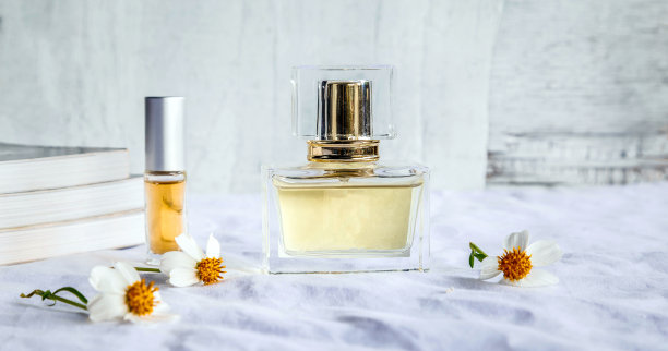 金色的香水和小香水瓶，白布背景上有一朵白花图片下载