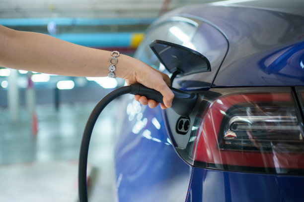 女子给电动汽车充电。图片下载