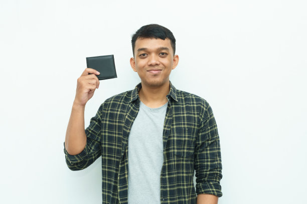 年轻的亚洲男子微笑着拿着黑色的钱包图片下载