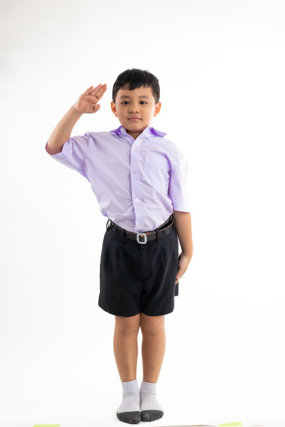 像警察一样表达敬意。年轻的亚洲可爱的男孩站在白底横幅。回到学校。图片下载