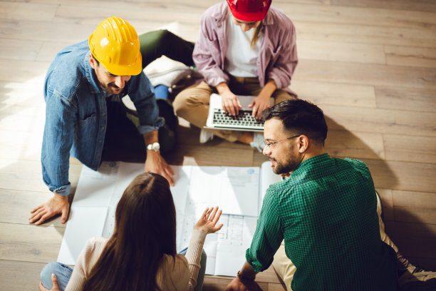 上图是年轻的工程师在地板上工作图片下载