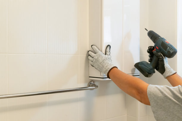 杂工在浴室墙上安装橱柜。图片下载