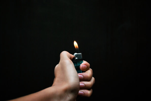 手拿着黑色背景上燃烧的打火机图片下载