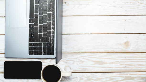 木制办公桌，笔记本电脑，智能手机，白色背景的咖啡杯。前视图。平的。经营理念。本空间图片下载