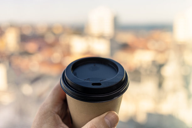 喝杯咖啡或茶，欣赏城市美景。享受，生活方式，外卖早餐理念。可回收的外卖咖啡杯。复制空间，模糊背景，选择性聚焦第一人称图片下载