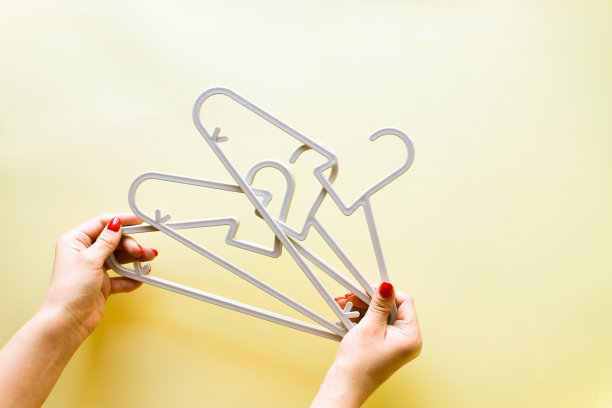 手拿着黄色背景的婴儿衣架图片下载