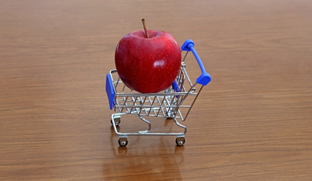 一个玩具购物车，上面有一个红苹果。购买健康食品的概念。图片下载