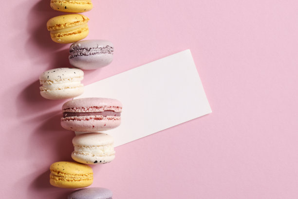 节日的概念。邀请卡、周年纪念卡、生日聚会卡。框架，模拟复制空间。粉红色背景上的彩色马卡龙。图片下载