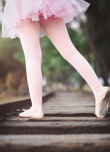 美丽的小女孩穿着芭蕾舞服在公园里玩耍，在火车轨道上快乐地笑着尖叫着图片下载