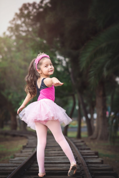 美丽的小女孩穿着芭蕾舞服在公园里玩耍，在火车轨道上快乐地笑着尖叫着图片下载