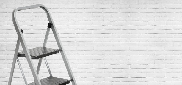 白色砖墙背景上的铝制梯子图片下载