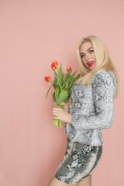 穿着蛇装的金发女人手里拿着郁金香花束图片下载