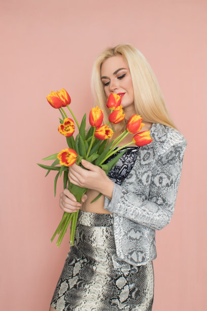 穿着蛇装的金发女人手里拿着郁金香花束图片下载