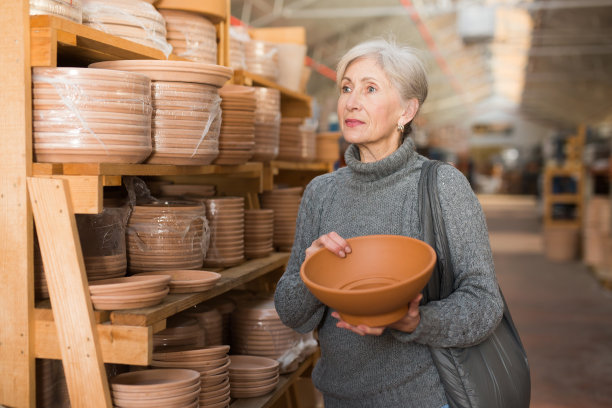 一位年长的女士正在寻找花盆，以便在温室里种植植物图片下载