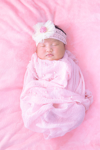 新生儿，特写漂亮的熟睡男婴。新生婴儿睡在毯子上，画面美丽，七天，新生婴儿戴大布，布玫瑰头带。图片下载