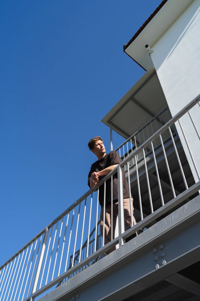 低角度的年轻人站在附近的公寓大楼旁图片下载