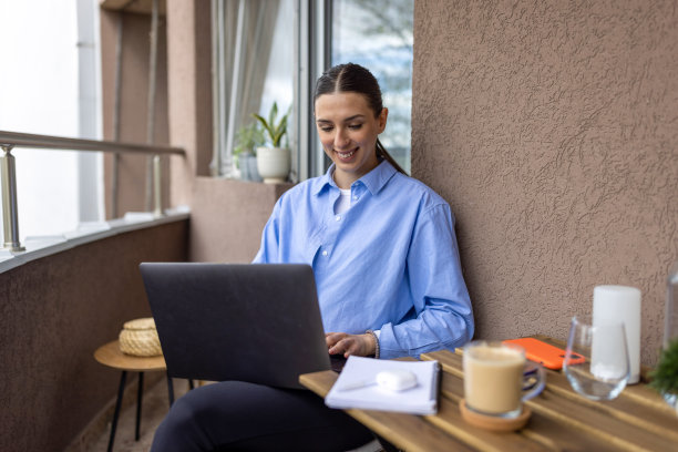 年轻女子早上在阳台上使用笔记本电脑图片下载