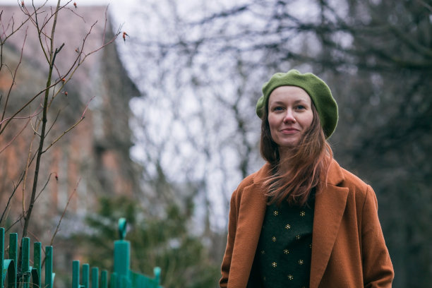 早春时分，一位30多岁的年轻女子戴着贝雷帽，穿着时髦的外套，走在城市里。现代的生活方式。图片下载