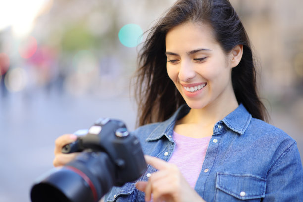 快乐的摄影师检查相机上的照片图片下载