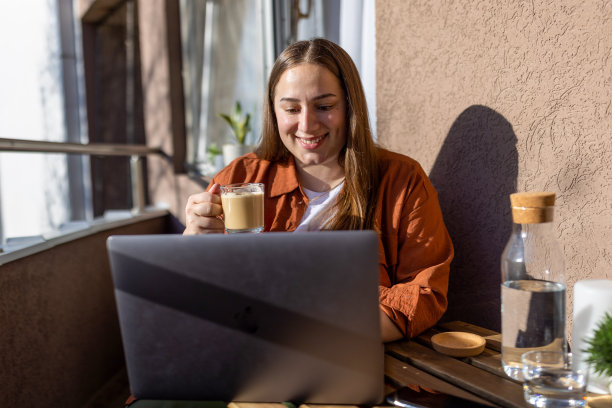 年轻女子早上在阳台上使用笔记本电脑图片下载
