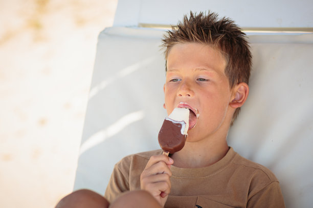 帅哥坐在沙滩上吃冰淇淋图片下载