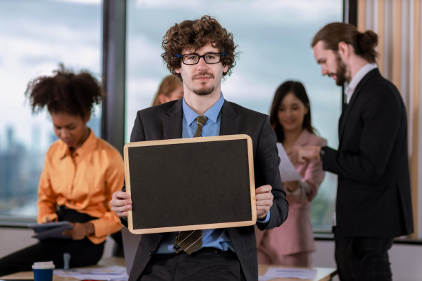在明亮的现代办公室里，英俊的商人手持黑板机图片下载