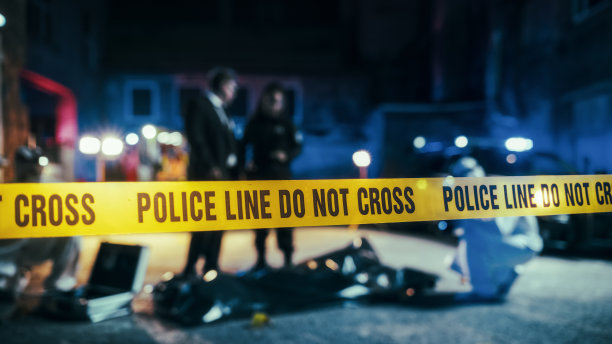 犯罪现场警戒线特写，显示“警察警戒线，禁止跨越”字样。限制公众进入区域。背景中有执勤警察。具有红色和蓝色霓虹灯的电影散景效果图片下载