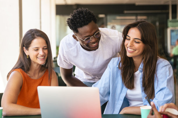 一群快乐的学生朋友坐在咖啡厅里看着笔记本电脑图片下载