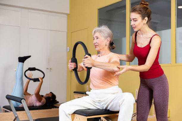 年轻教练帮助老妇人练习阻力环图片下载