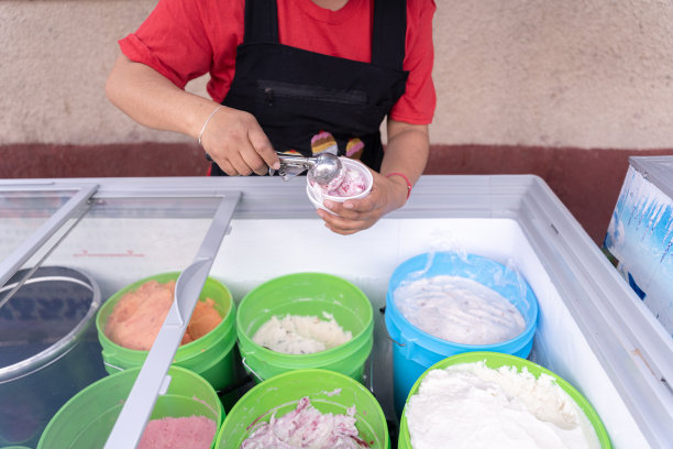 一位西班牙裔成年妇女在街上用杯子盛着黑莓奶酪冰淇淋图片下载