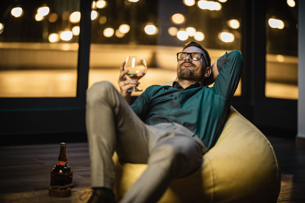 成功完成一天的工作后，年轻的商人坐在包椅上喝着白兰地图片下载