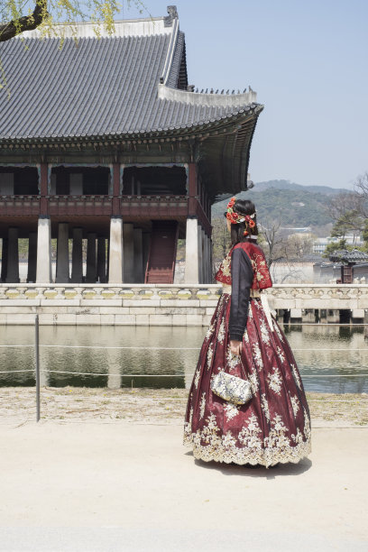 在景福宫古建筑的背景下，身穿漂亮红色韩服的年轻女子(后景)。图片下载