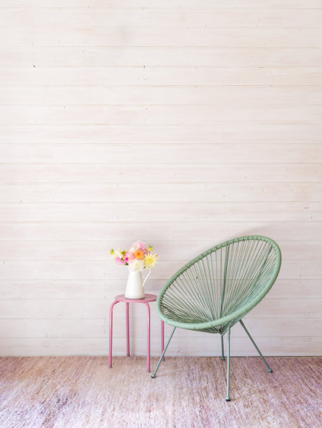 在绿色椅子旁边的粉红色凳子上，白色罐子里的彩色大丽花垂直视图图片下载