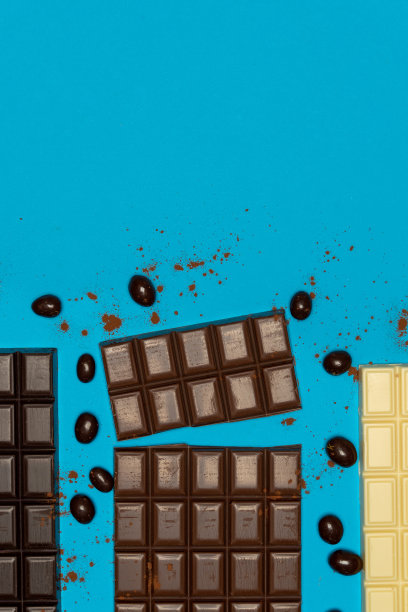 蓝色背景上的黑巧克力、牛奶巧克力和白巧克力的俯视图图片下载