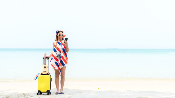 夏天的假期。时尚女性在海滩背景下用智能手机上网图片下载