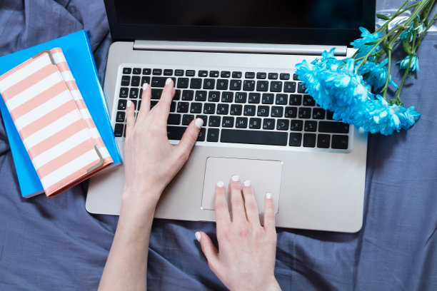 手，电脑键盘，床顶视图。职场背景，在家办公，记事本和鲜花图片下载