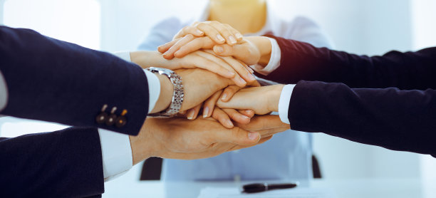 在阳光明媚的办公室里，业务团队双手合拢，表现出团结。一群人手拉手，代表着友谊和团队合作的理念图片下载