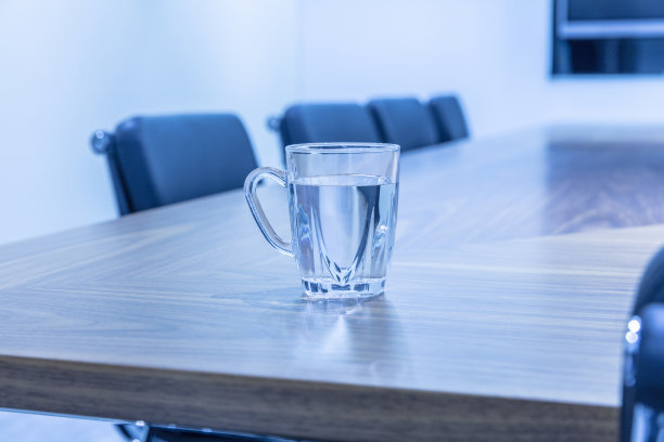 会议室的近景，桌子上放着水杯，扶手椅和大显示器图片下载