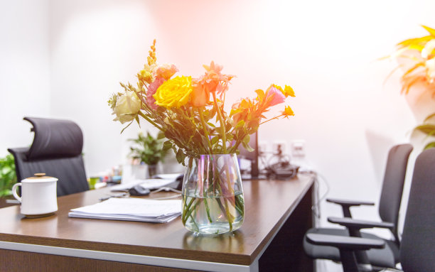 空房间里有三把椅子和一个玻璃瓶，桌子上放着水，还有黄色、粉红色的花图片下载