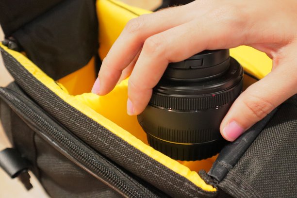 女孩把照相机镜头放进书包里图片下载