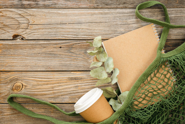 环保棉网袋与外卖杯和笔记本在木制背景。图片下载