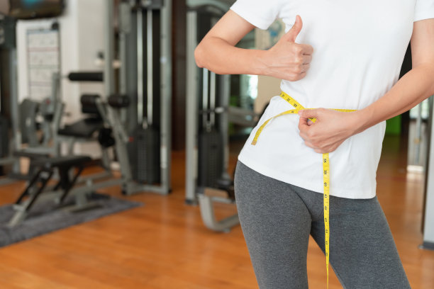 节食和节食。美女苗条身材用卷尺量。穿着运动服的女性实现了健康生活的减肥目标，痴迷于瘦，细腰，营养学家。图片下载