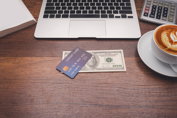 工作台概念。办公室木桌上的一张蓝色信用卡模型、一本书、一台笔记本电脑、一台计算器和一个咖啡杯。图片下载